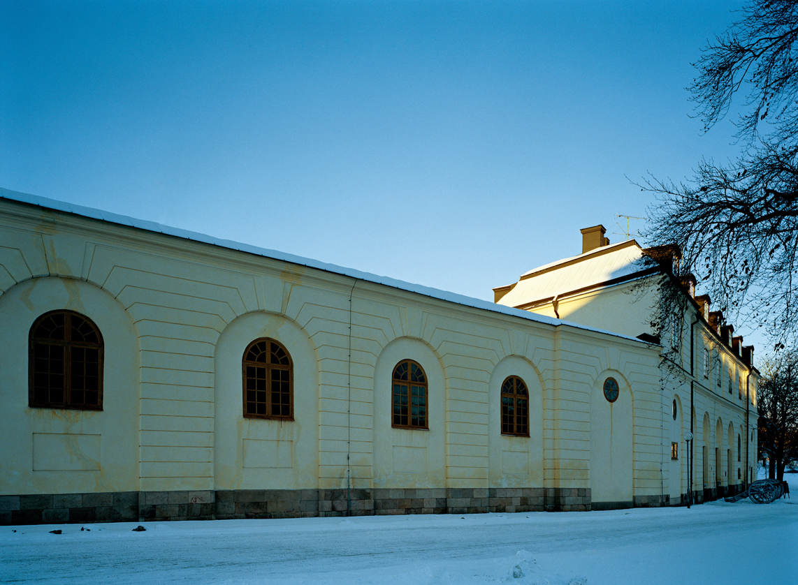 Slotts-stallet vid Drottningholm. En låg klassicistisk byggnad i ljus-gul puts.