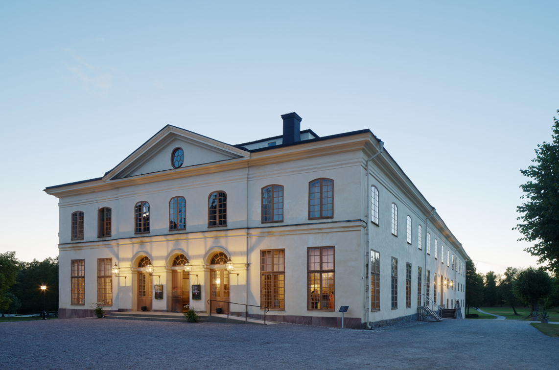 Drottningholms slottsteater. En ljus klassicistisk byggnad i souterräng. Sommarkväll.