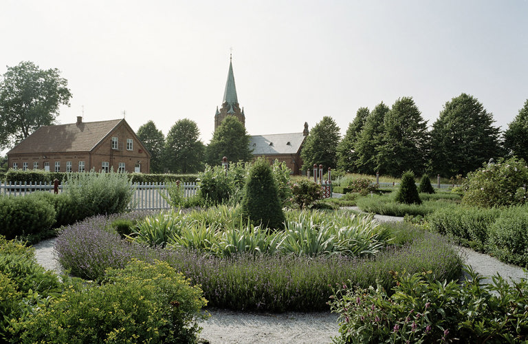 Den rekonstruerade renässans-trädgården på Ven. I bakgrunden Allhelgona-kyrkan. Sommar, blommor och grönska.