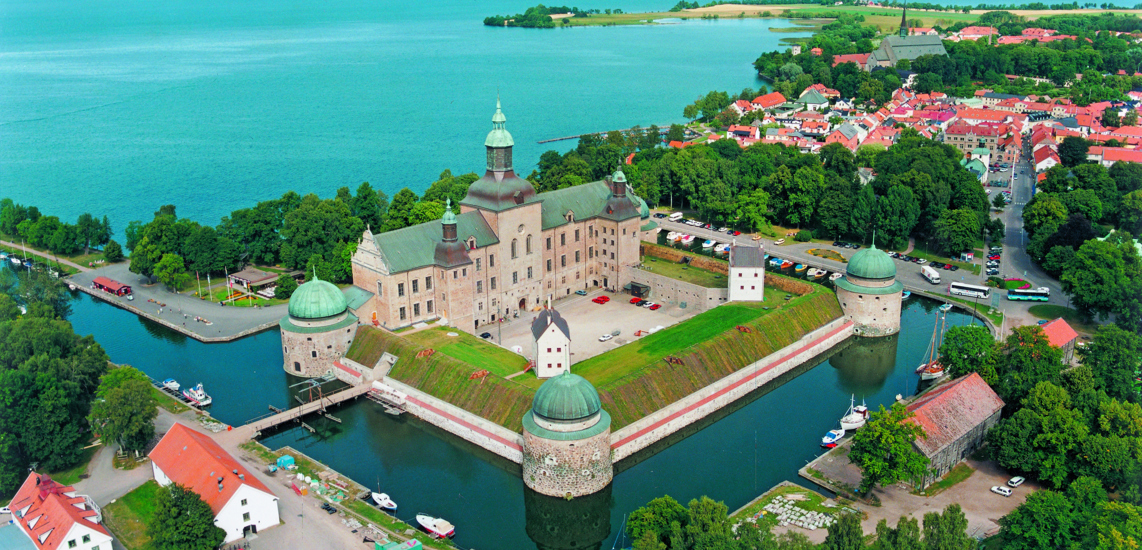 Flygfoto av Vadstena slott. Utsikt över Vadstena och Motalabukten. Sommar och grönska.
