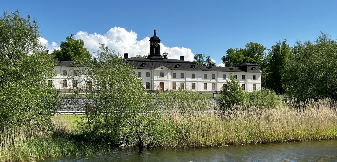 Svartsjö slott med Svartsjöviken i förgrunden. Sommar och grönska.