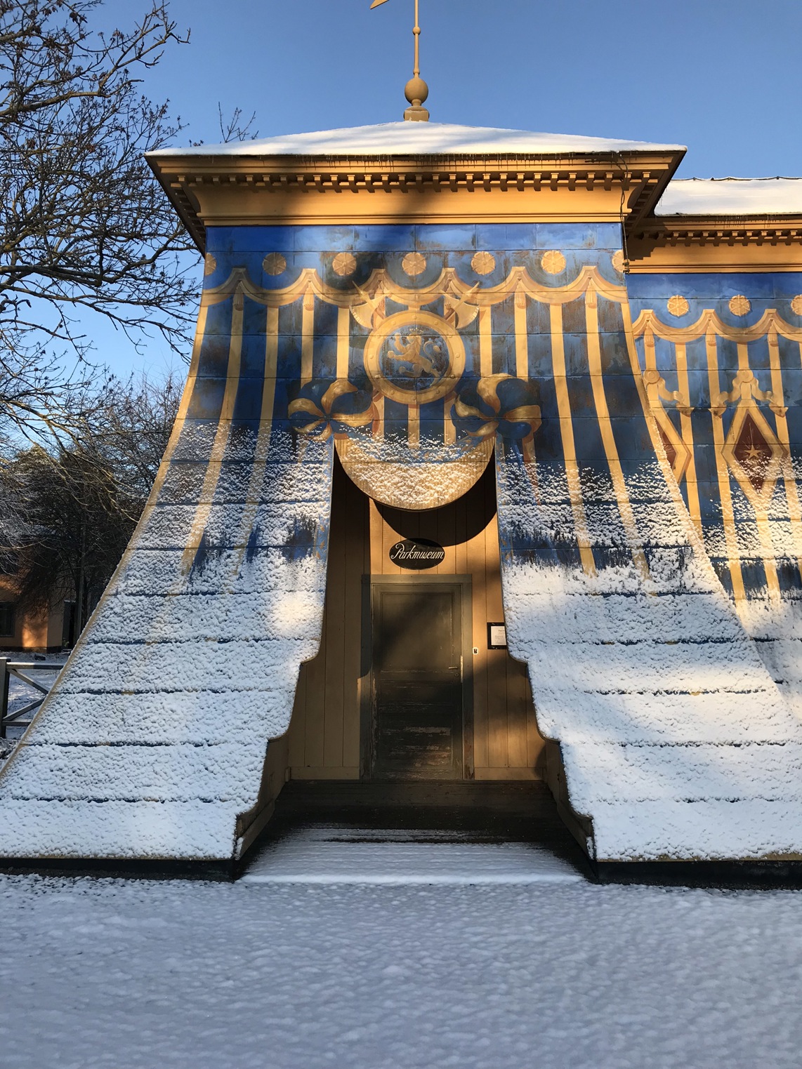 Mellersta koppartältet i Hagaparken. Entrén till Haga parkmuseum, genom en enkel trädörr. Vinter, snö och sol.